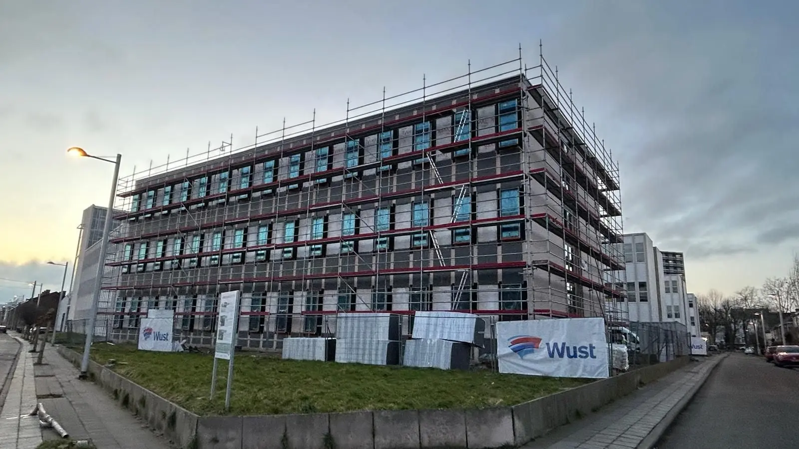 Immeuble de quatre étages de l’Université de Mons sous échafaudage, au crépuscule